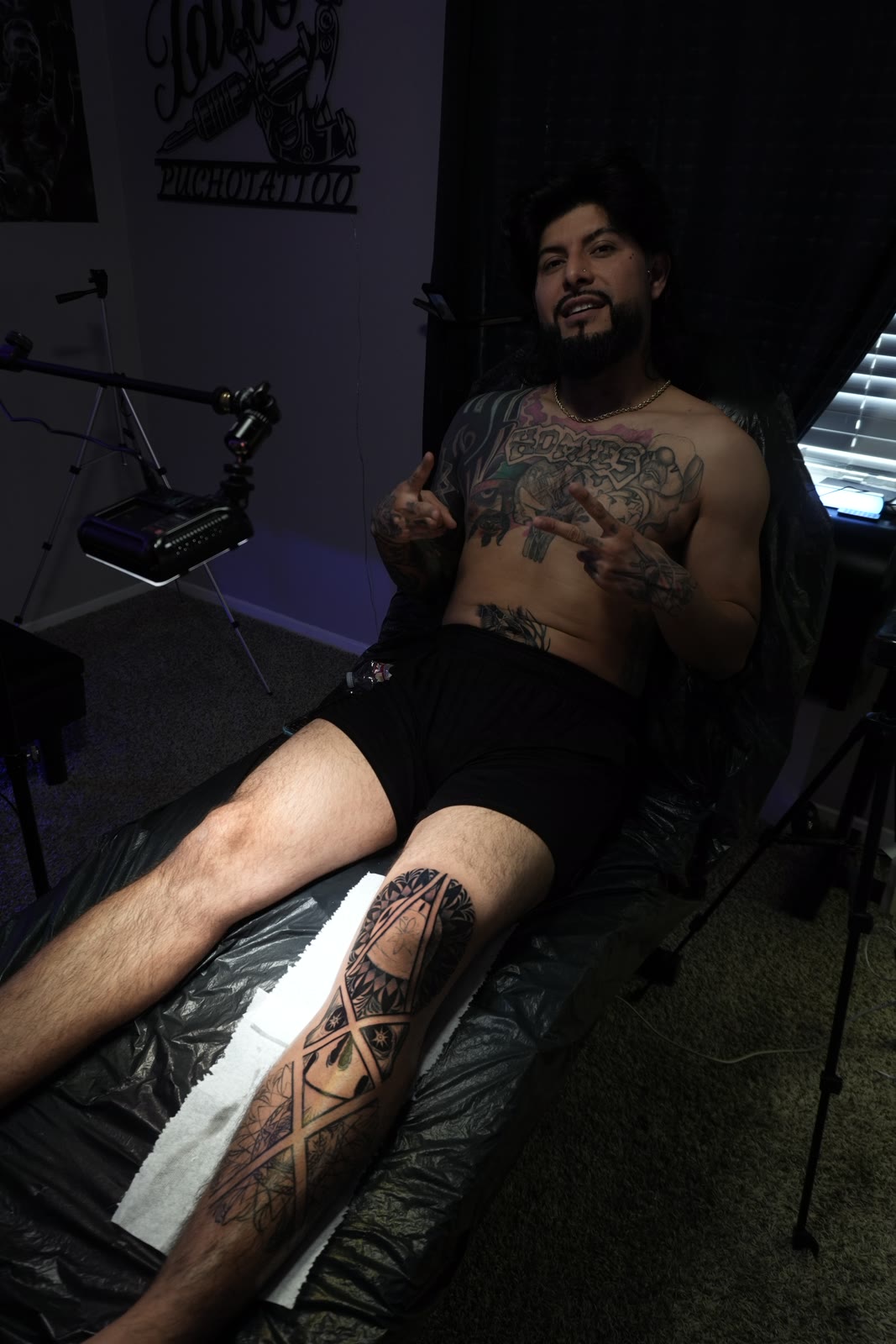 Cliente con pierna geométrica terminada y muro PUCHOTATTOO en el estudio